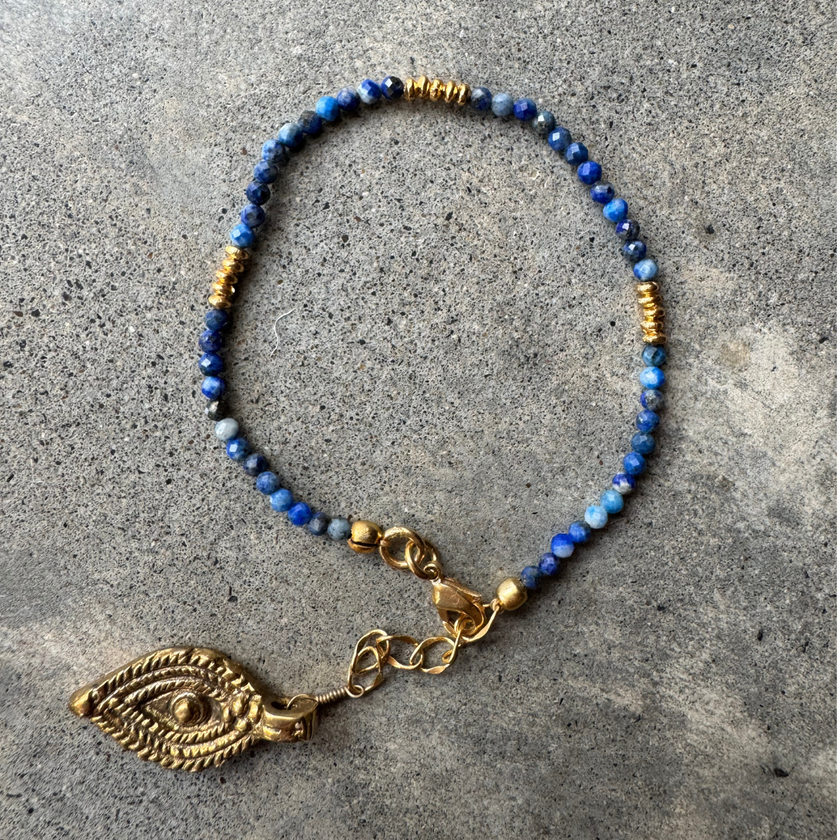 Marie Lapis Lazuli Bracelet with a brass charm, laid flat