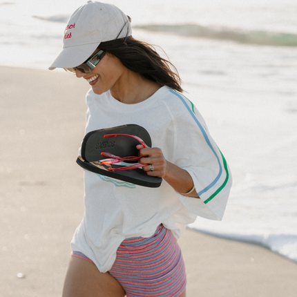 Woman on the beach carrying Cherry Bomb Jelly Wide flip flops by Sandos