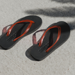 Pair of Cherry Bomb Jelly Wide flip flops by Sandos on concrete