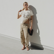Woman standing against a white wall holding Cherry Bomb Jelly Wide flip flops by Sandos