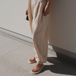Woman in linen trousers standing in Ecru Jelly Square flip flops by Sandos