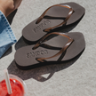 Pair of Espresso Jelly Tapered Platform flip flops by Sandos beside a drink and denim