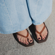 Close-up of Espresso Jelly Tapered Platform flip flops by Sandos worn with wide-leg jeans