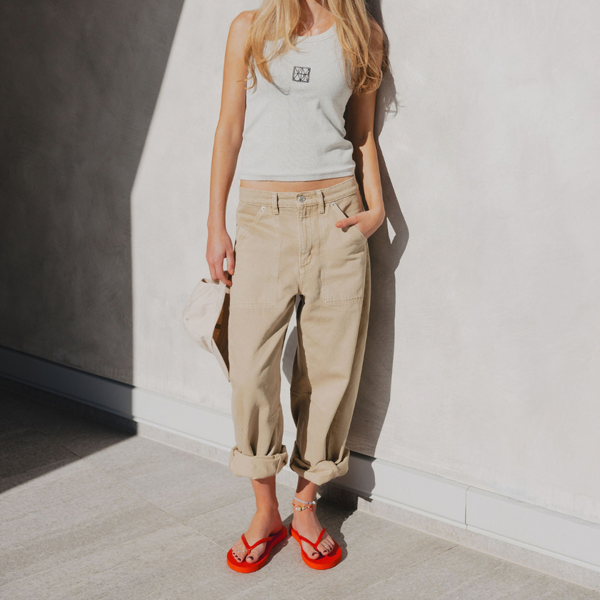 Woman in beige trousers and a white top wearing Red Boyfriend Wide flip flops by Sandos