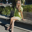 Woman in a green dress sitting on a bench wearing Truffle Boyfriend Wide flip flops by Sandos